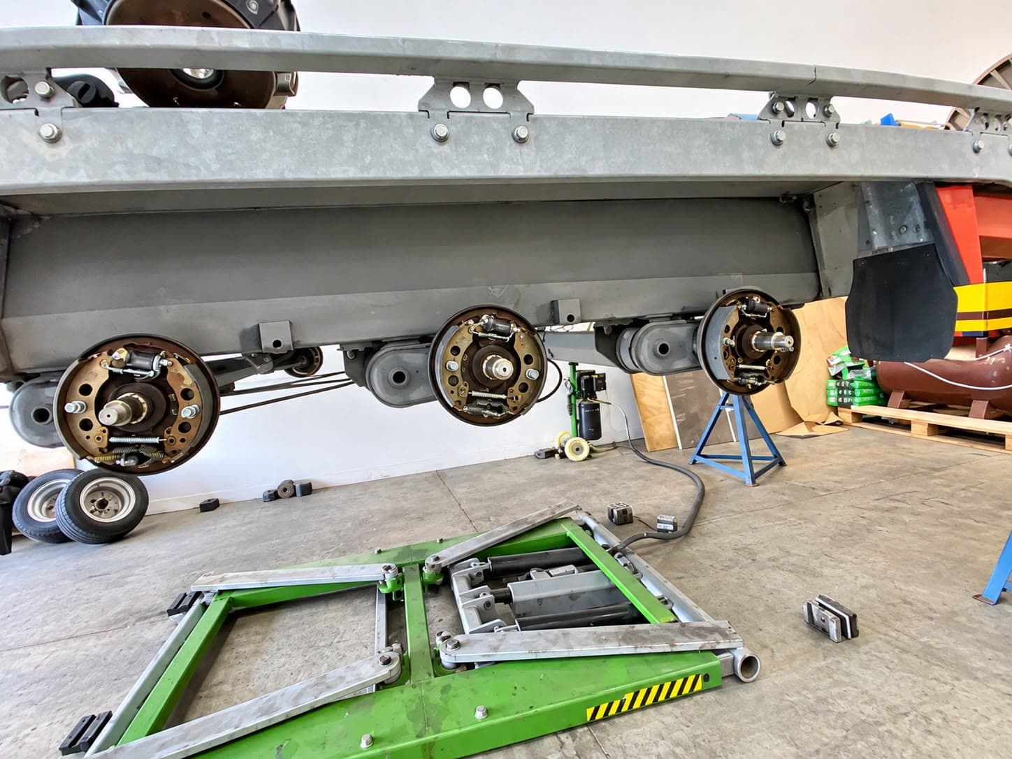 Tri-axle trailer up on the lift with all the hubs off, showing the brakes